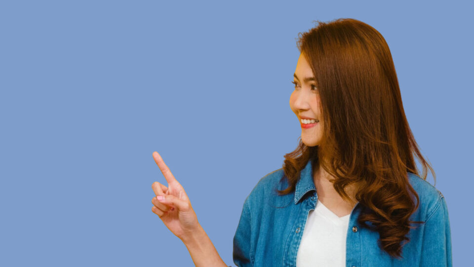 笑顔で近くを指差す女性の画像