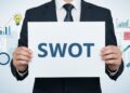 「SWOT」の紙を持つ男性の手元画像