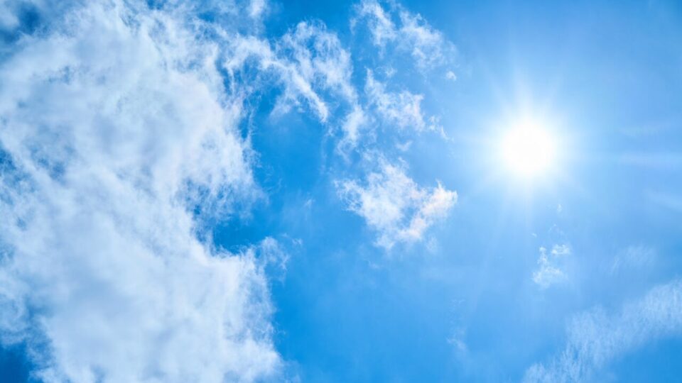 青空に輝く太陽と雲の画像