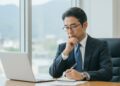 パソコンを見て悩んでいる男性の画像