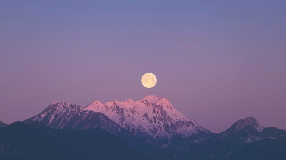 紫色の空に浮かぶ月と山の画像