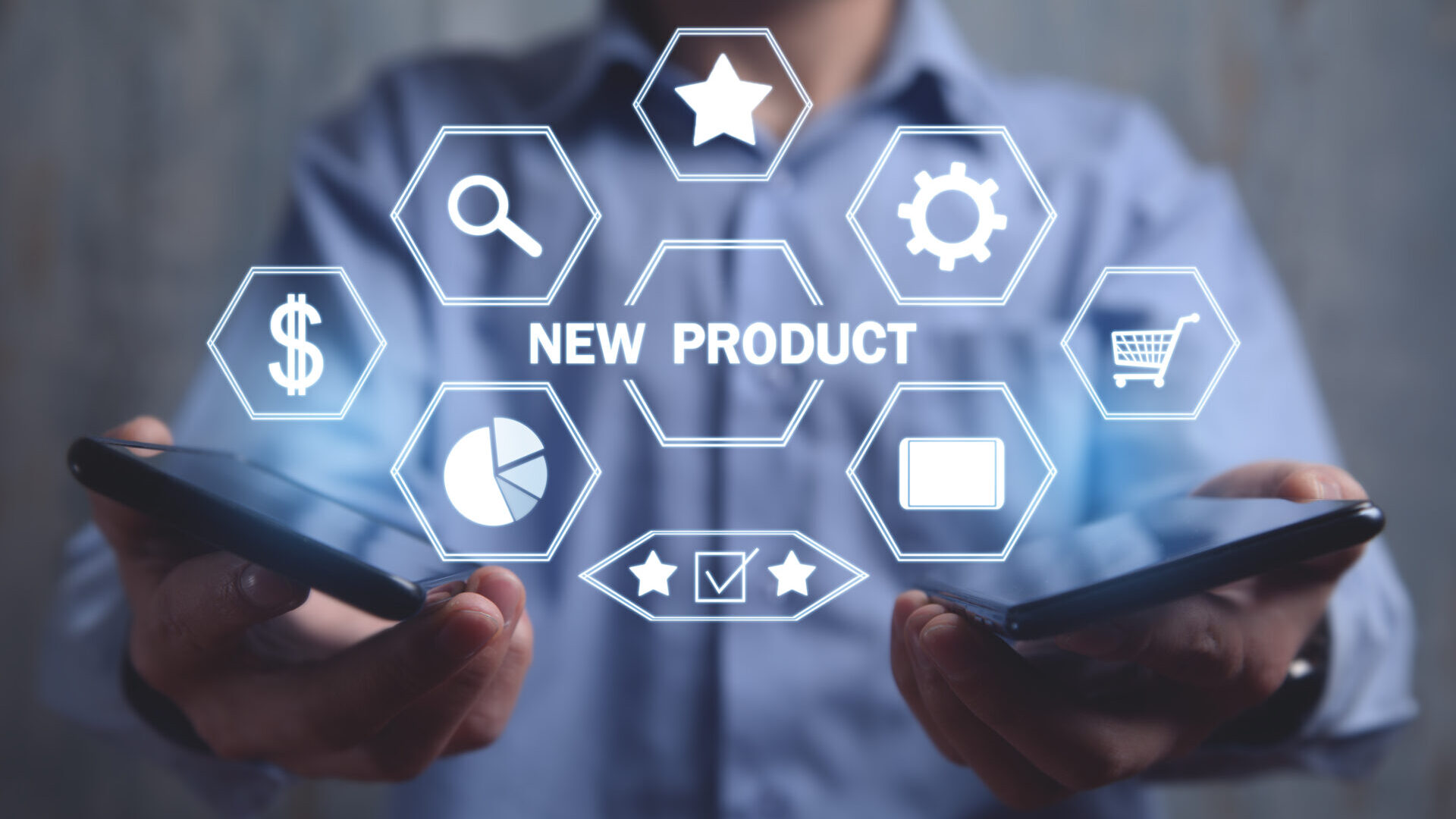 “NEW PRODUCT”の文字と、商品開発に関連するアイコン（星、歯車、カート、グラフ、ドル記号など）が表示されたホログラムを、2台のスマートフォンを持った人物が操作してる画像