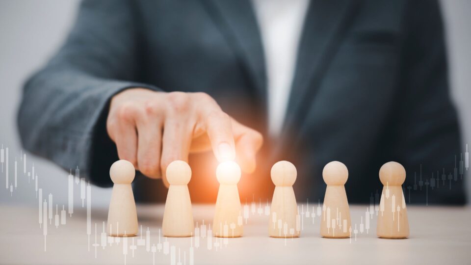 スーツ姿の人物が木製の駒を指し示し、リーダーシップを表現している画像